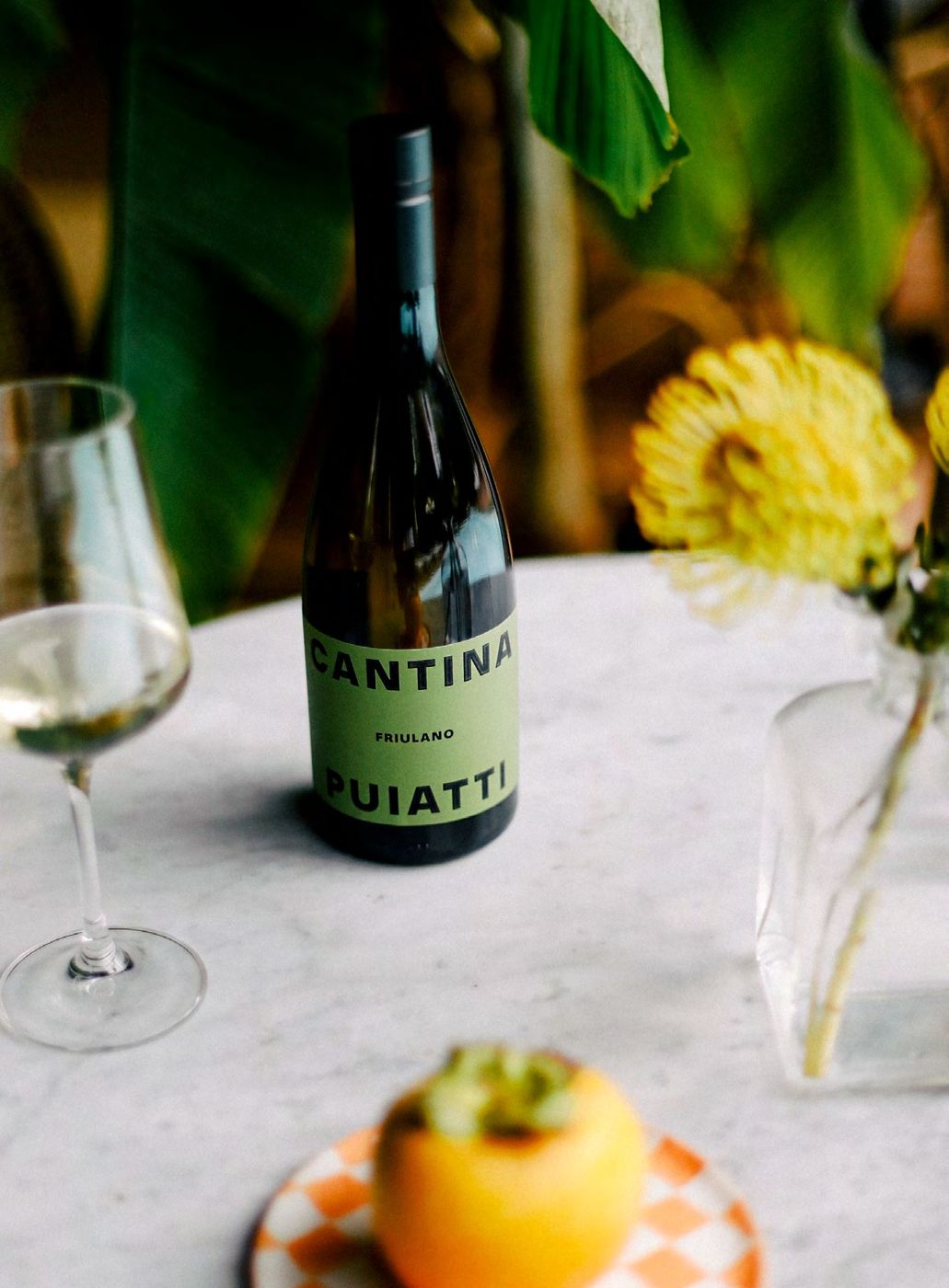 Bottiglia di Cantina Puiatti e calice di vino bianco su una tavola apparecchiata